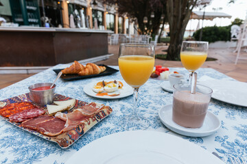 Continental breakfast on a terrace with orange juice, fruit, cocoa, coffee, pastries, cold meats, tomato, etc.