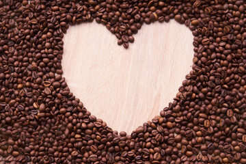 The coffee beans arranged in a heart shape on wooden background.Coffee beans are laid out in a heart shape