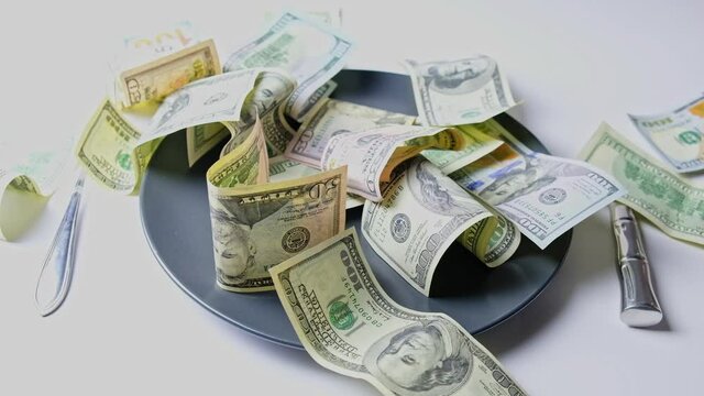 U.S. dollars drops on a plate with knife and fork.