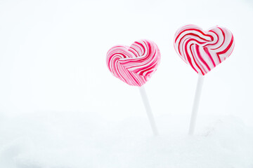 Two pink heart-shaped lollipop. Caramel candy on stick on white background. Sweet gift for valentines day.