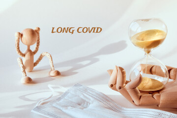 Long covid, post-covid syndrom, long haulers. Tired wood toy human figure. Hourglass in wooden...