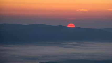 Wstające słonce znad górskich szczytów we mgle  / The rising sun over the mountain peaks in the fog