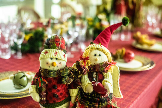Wonderful table for the celebration of Christmas set up with plates, glasses, wine glasses, and golden cutlery with ornaments in red tones. Christmas ornaments on the table. - Powered by Adobe