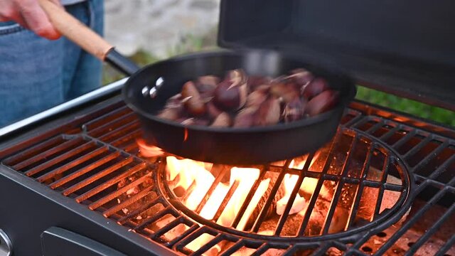Roasted chestnuts and maroni over the fire in a special steel pan. Traditional Italian autumn delicacies. Party at a country house with friends. High quality 4k footage