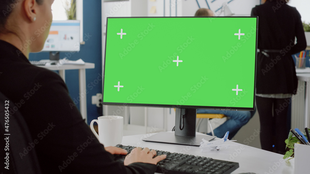 Poster close up of computer with horizontal green screen on desk. woman with business job working on monito