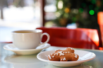 Gingerbread man and a cup of tea on a table in a cafe with selective focus and copy space. Cozy winter atmosphere