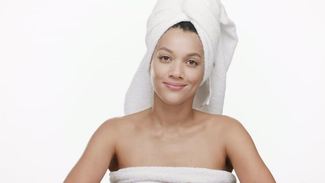 Funny good-looking young slim African American woman with a towel on her hair throws away orange razor on white background | Unwanted body hair removal concept