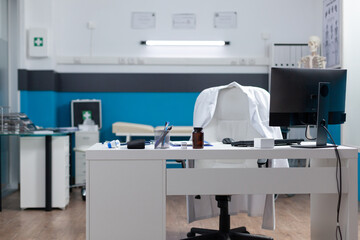 Empty medical office equipped with modern furniture ready for clinical examination. Hospital workplace with nobody in it having disease documents on table. Medicine services