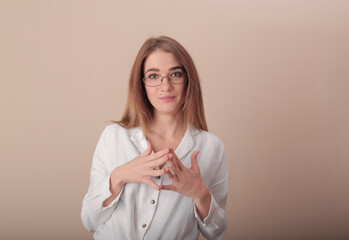young beautiful girl in the image of a teacher. in glasses and a white blouse. folded her hands in...