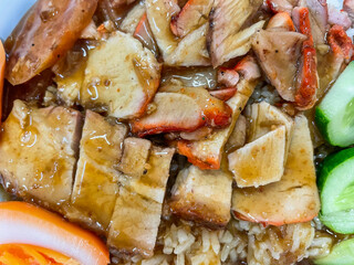 Crispy belly pork on rice with barbecue red sauce and Egg topped. It is a delicious menu of Thai. Close up photo.