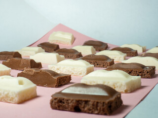 Slices of black and white chocolate on paper. Slices from a bar of chocolate.