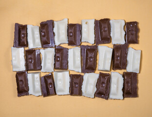 Slices of black and white chocolate on a beige background. Slices from a bar of chocolate.