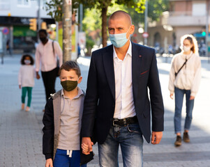 Fototapeta premium caucasian man and boy in masks on city street