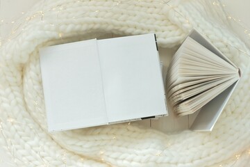 Winter books reading. Open white books with blank sheets with white knitted scarf and garland.Cozy mood. Winter Season Christmas books.