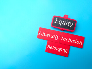 Colored wooden board with text Equity,Diversity,Inclusion,Belonging on blue background.