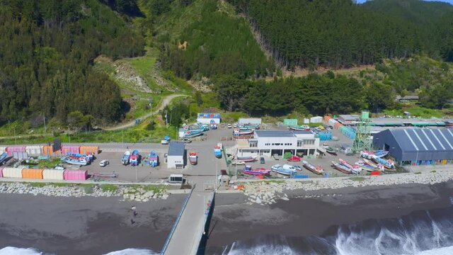 port or caleta meguellines, constitucion chile drone shot sunny day with fishing boats traveling out