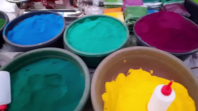 Colorful powder for sale on the festive occasion of Holi in India. Holi colorful powder, piles of powdered dyes, festival celebration herbal Holi gulaal colors in a Plastic big bowl at the roadside.