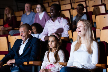 Cheerful family watching a movie and eating popcorn in cinema. High quality photo