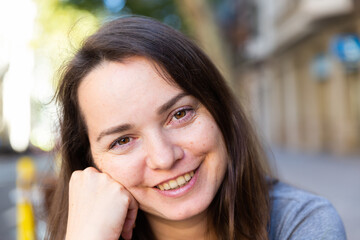 Obraz premium Portrait of smiling longhaired woman standing outdoors in city