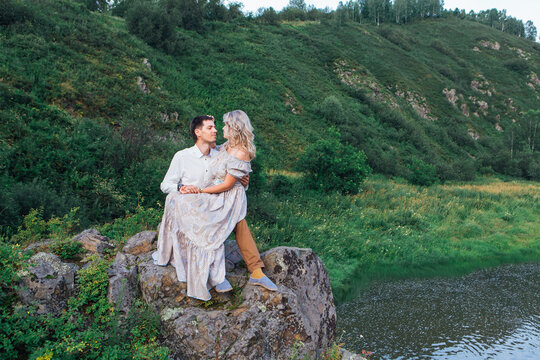 Romantic inloved couple sitting on rocks by the river.