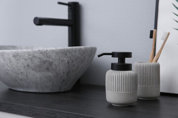 Dispenser of liquid soap and toothbrushes near sink in bathroom. Space for text