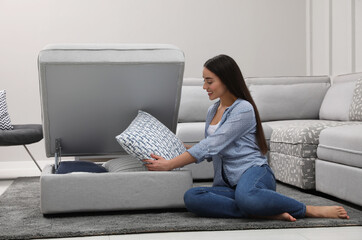 Woman taking soft pillow from modular sofa section in living room
