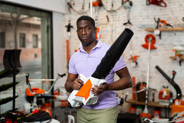 African-american man with leaf blower standing in gardening tool store.