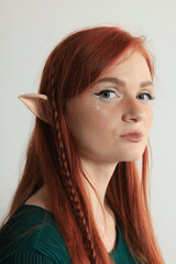Beautiful redhead elf girl on light background