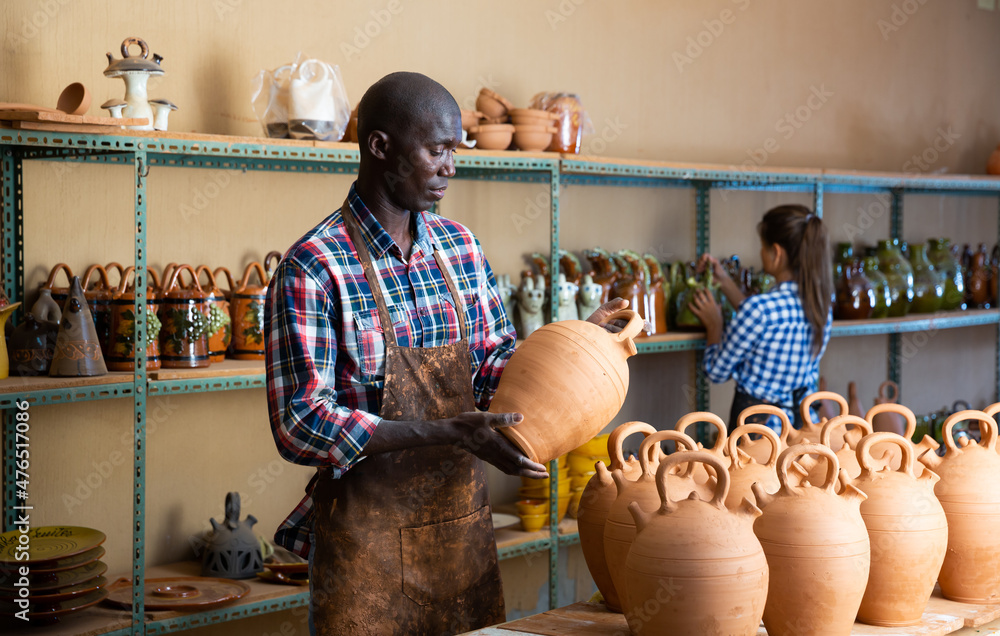 Wall mural Two positive smiling potters in the process of work at the workshop. High quality photo