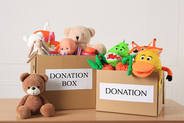 Donation boxes and different child toys on wooden table