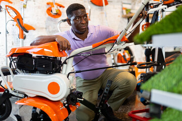 African-american man choosing cultivator in gardening tools store.