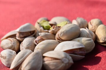 Obraz na płótnie Canvas Green fresh pistachios Nuts on red background