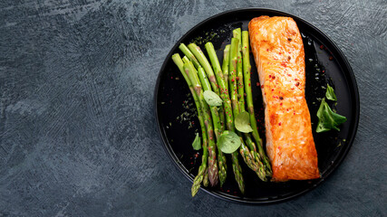Baked salmon with asparagus on gray background.