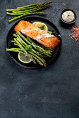 Baked salmon with asparagus on gray background.