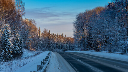 Country road among the winter forest covered with white snow.