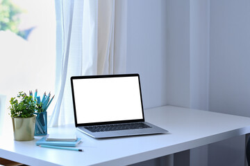 Fototapeta premium Mock up computer laptop, books and houseplant on white table in comfortable living room.