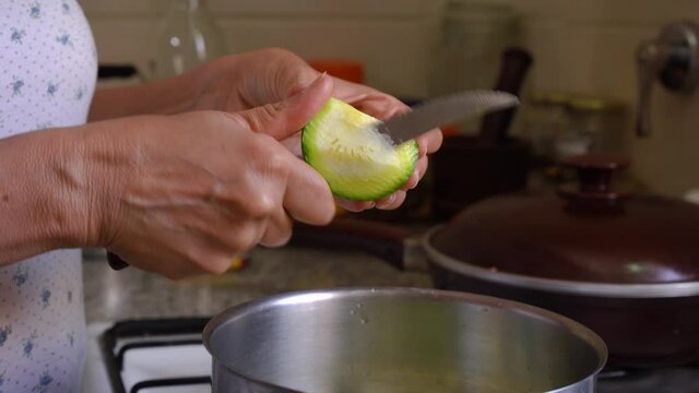 Female Hands Holding And Cutting Fresh Green Summer Squash In The Kitchen. close up