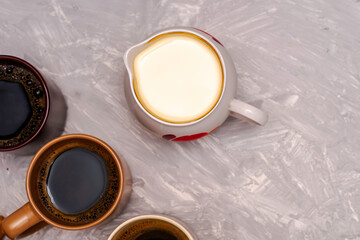 a jug of milk and three mugs of coffee on the table top view