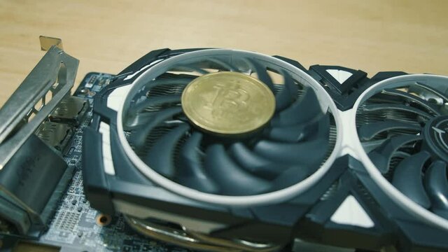 Black Graphic cards with golden bitcoin coin and rotating fan Ehtereum Crypto mining rig
