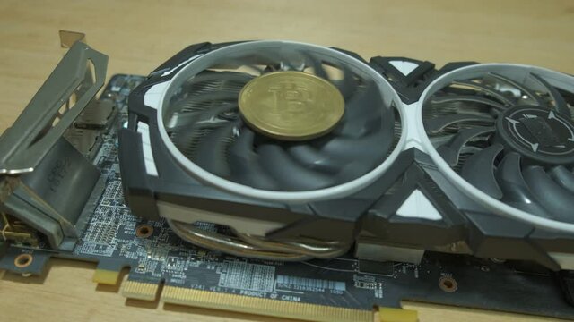 Black Graphic card with golden BTC coin and rotating fan Ehtereum Crypto mining rig