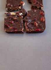 top view of chocolate bar pieces, homemade chocolate with whole nuts and dried fruits, copy space for text