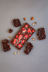top view of quality craft chocolate bar, freeze-dried strawberry's chocolate bar among nut's chocolate pieces