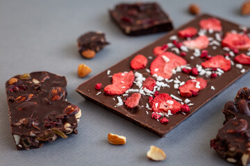 quality craft chocolate bars closeup, freeze-dried strawberry's chocolate bar among nut's chocolate pieces