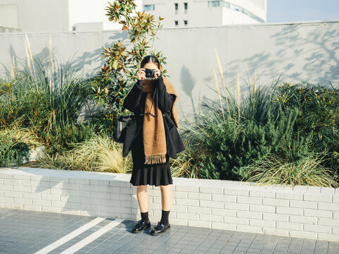マフラーを巻いてカメラを持つ若い女性