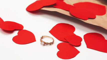 Marry me concept, wedding engagement ring with with paper envelope and paper hearts on white background. Happy valentines day present. Close up, copy space,