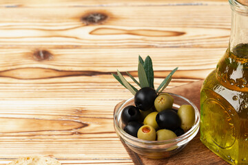 Olives and bottle of olive oil on wooden background