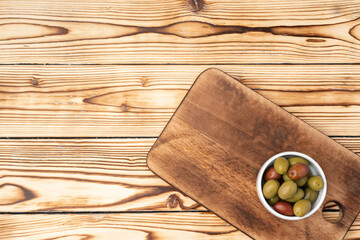 Olives in a bowl on wooden background, top view
