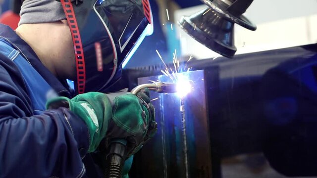 Masked welder performing welding work.