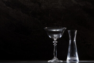 Empty cocktail glasses and containers in front of a dark marble tile background