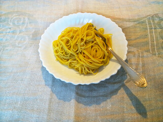 Budget cooked dish of spaghetti on white plate with fork. Cheap homemade food during Covid-19 lockdown. Economic and financial crisis concept. No products in supermarket. Inflation. Take out food.